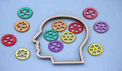 Brain with colourful cogs on purple background
