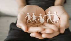 Open hand holding wooden people including one in wheelchair

