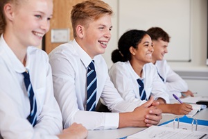 Secondary school students smiling sat at desks in classroom